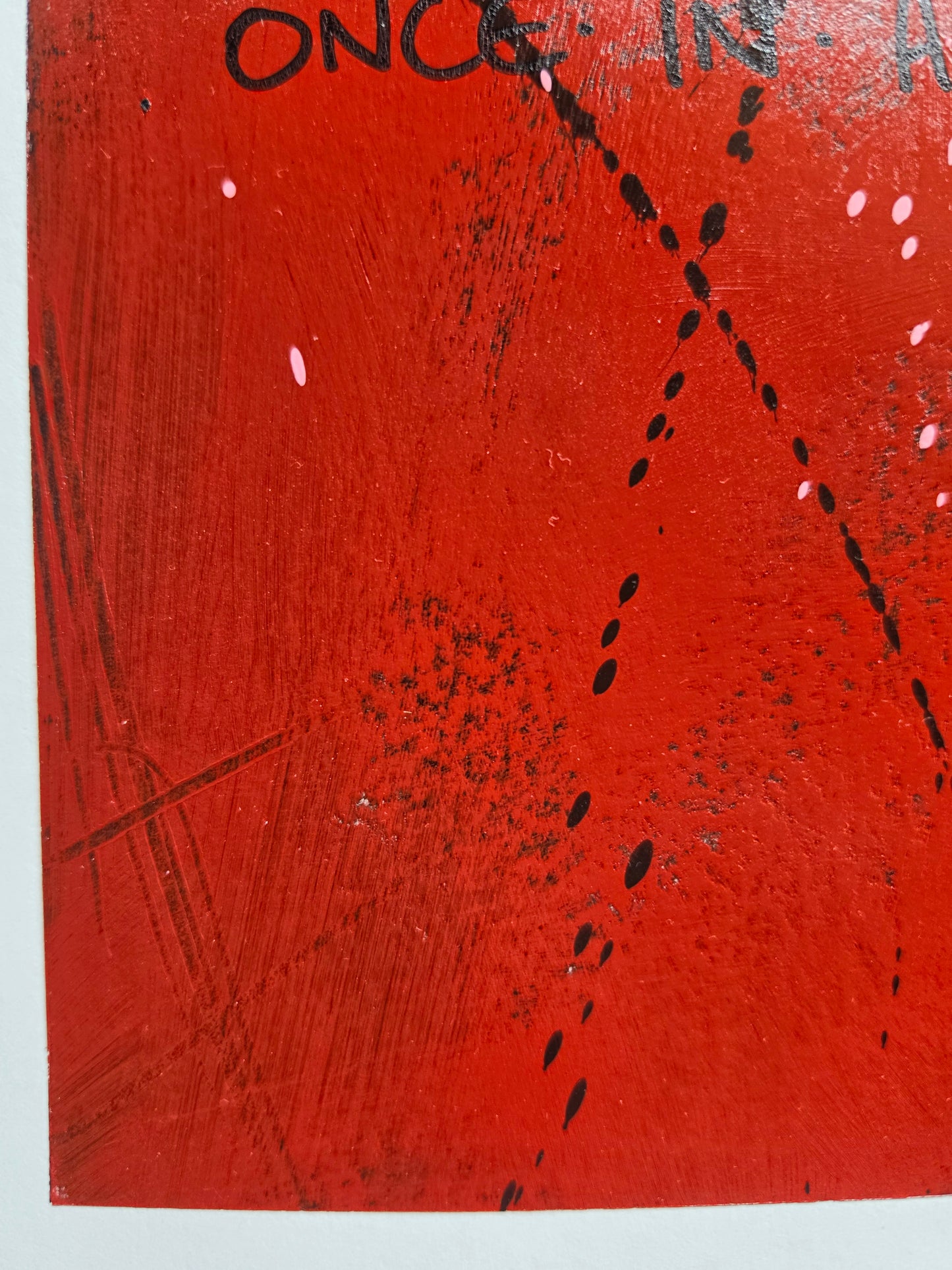 Close-up of a red paintinge with black markings, texture and paint spots in black and pink with white border