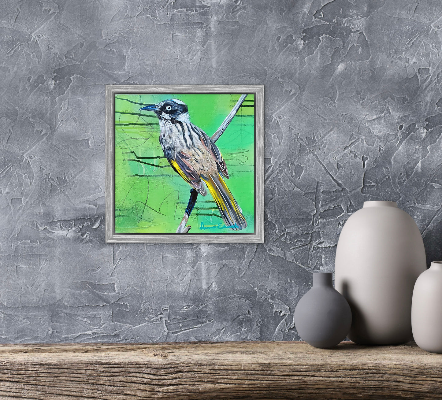 Framed artwork of a bird on a textured gray wall with decorative vases below.