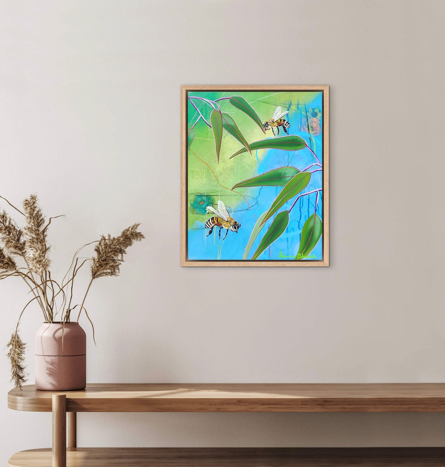 Framed artwork of bees on leaves above a wooden console table with a vase.