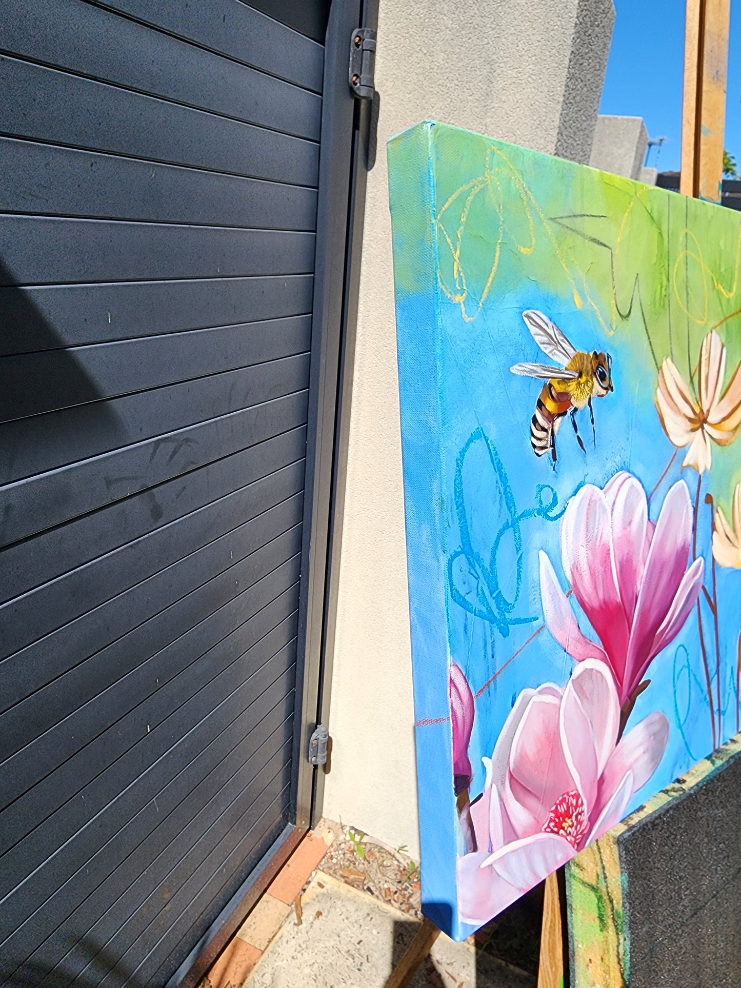 Colorful painting side view of a bee and flowers on a wooden easle