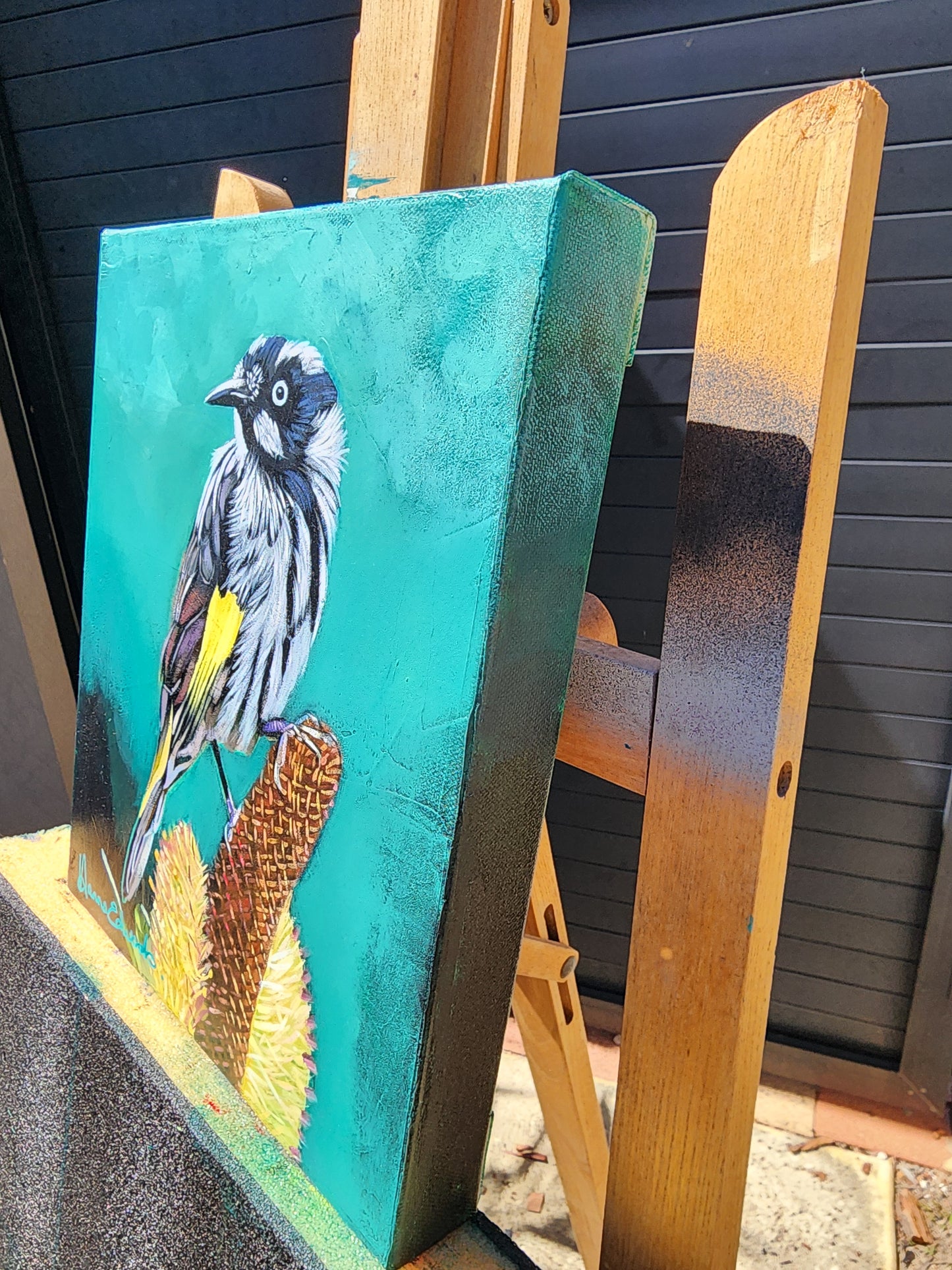 Bird painting on a wooden easle side view.