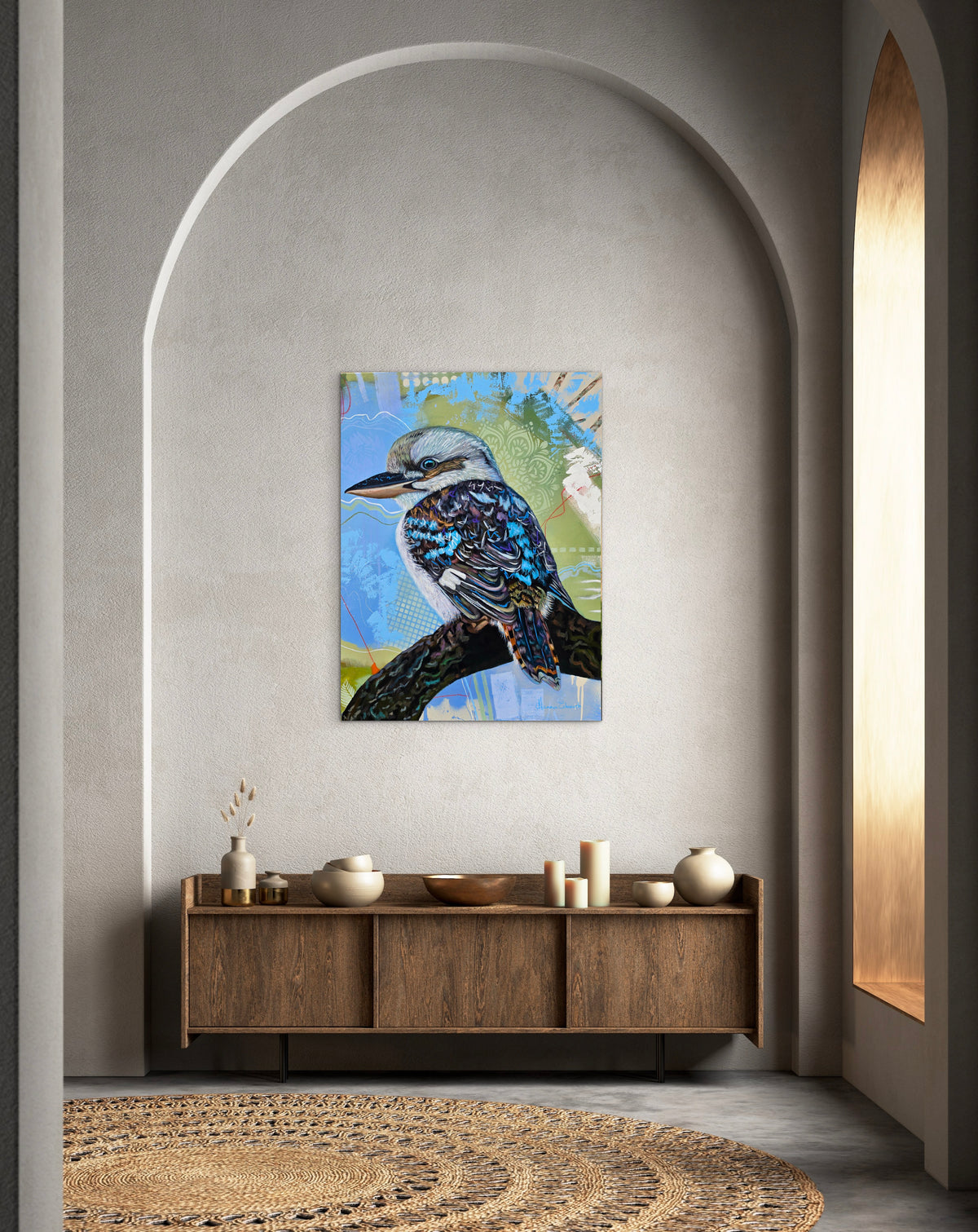 “Liberation” original kookaburra painting by Australian artist Hanna Edwards, displayed above a wooden sideboard in a neutral contemporary interior with an arched wall and natural light.