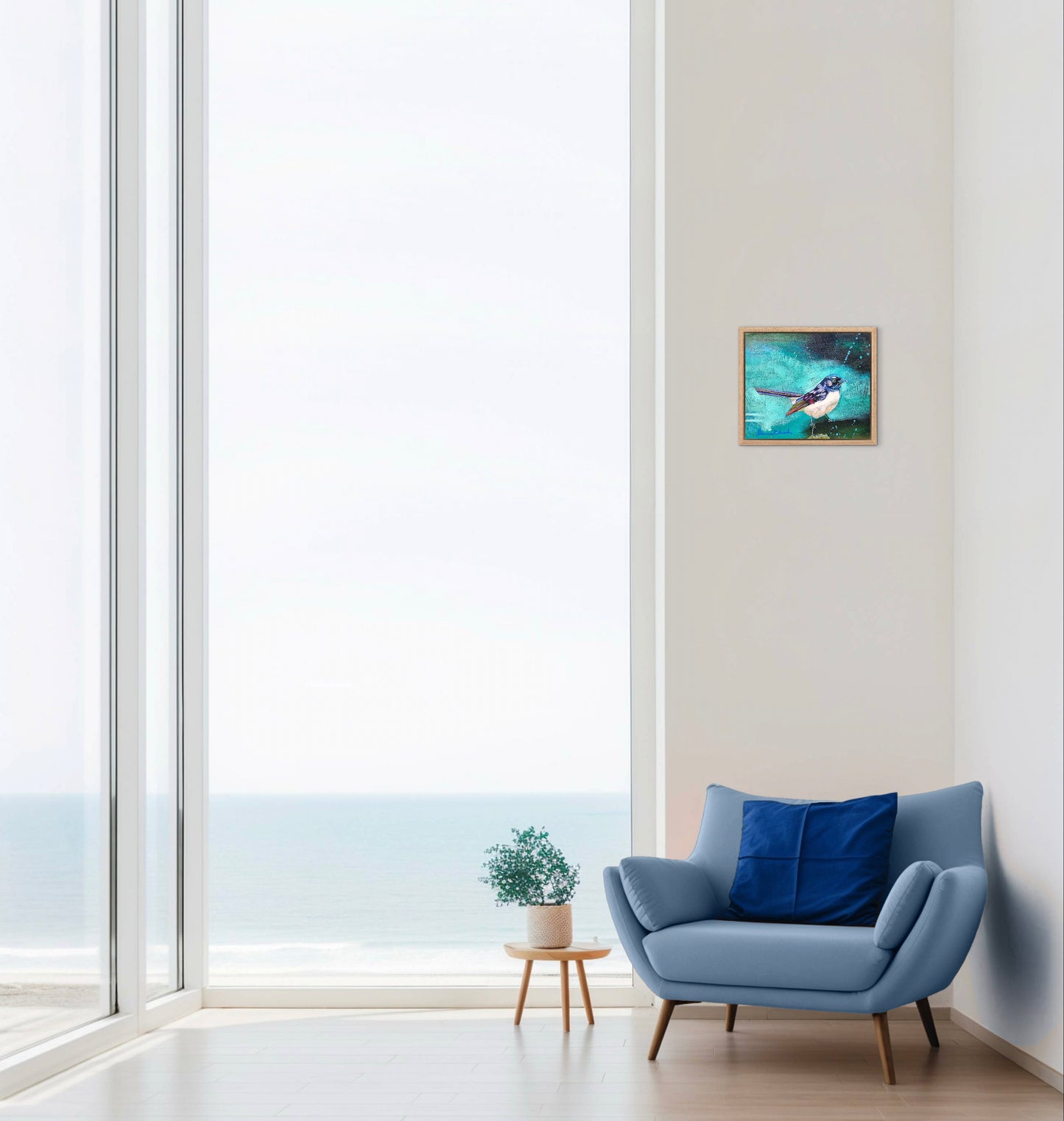 Modern living room with a blue armchair, small table, and framed artwork on a white wall.