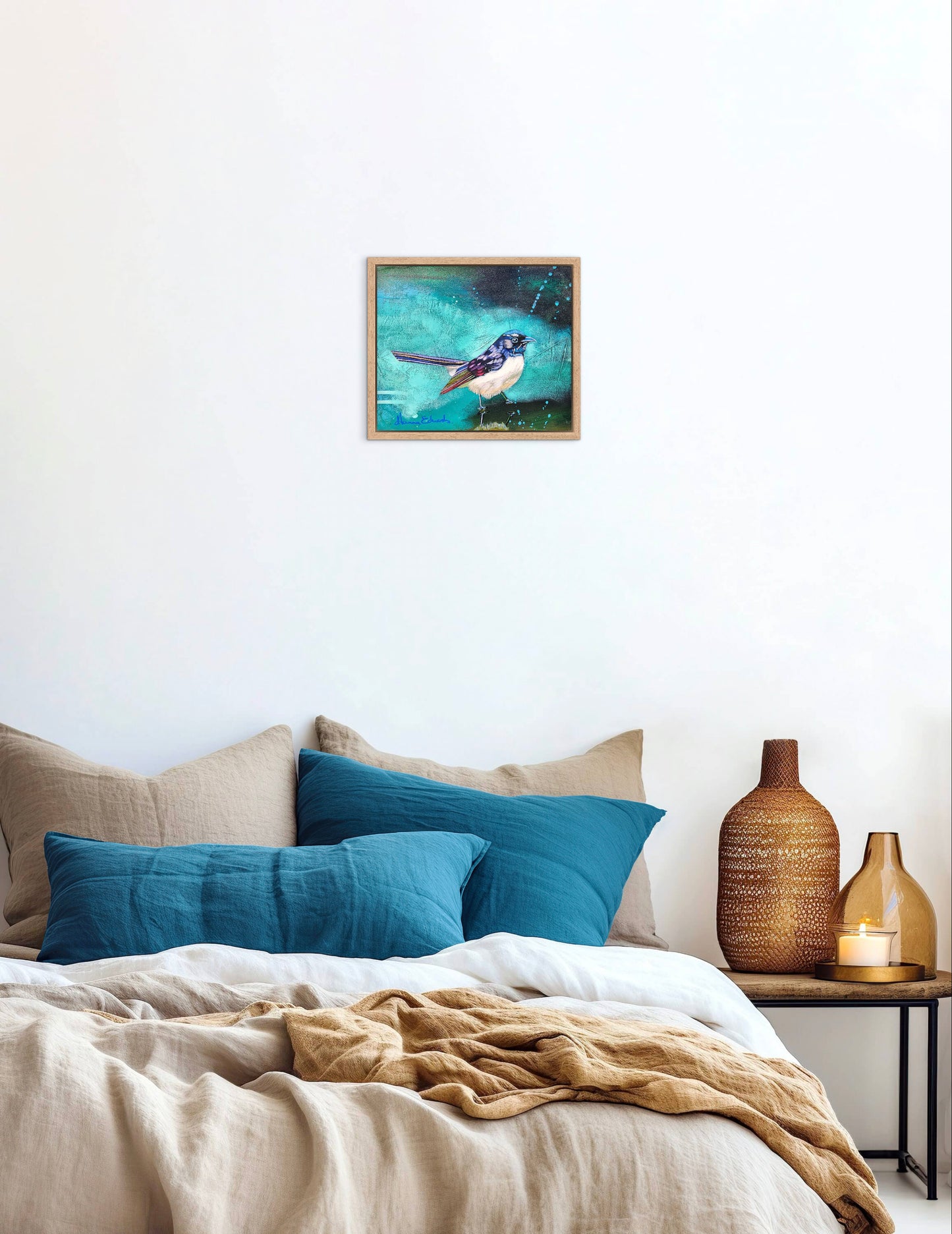 Framed artwork above a bed with blue pillows and decorative vases.