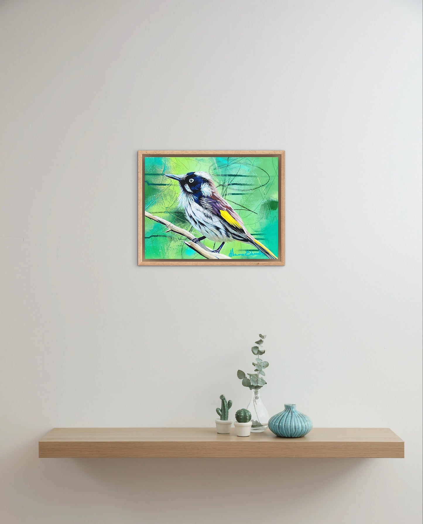 Framed artwork of a bird on a white wall above a wooden shelf with decorative items.