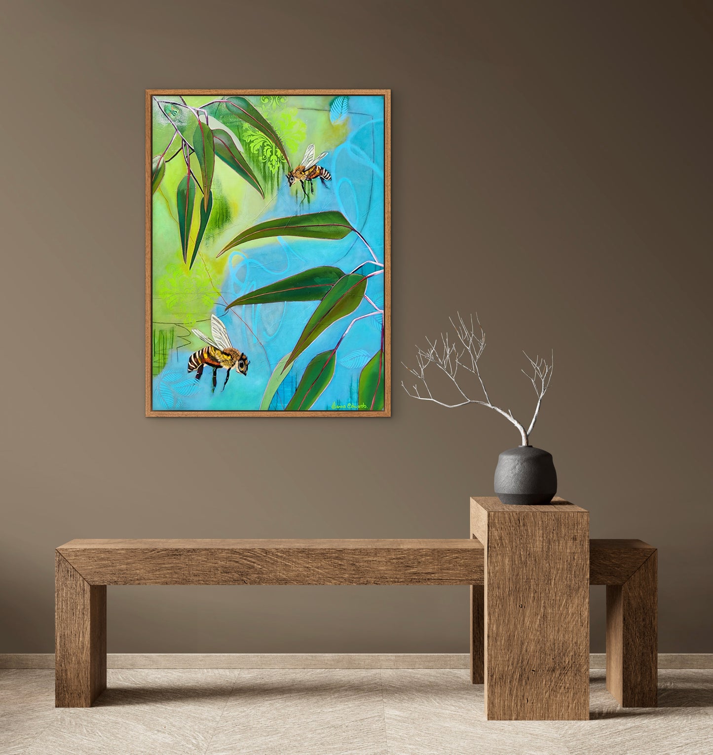 Framed artwork of bees and leaves on a wall above a wooden bench.