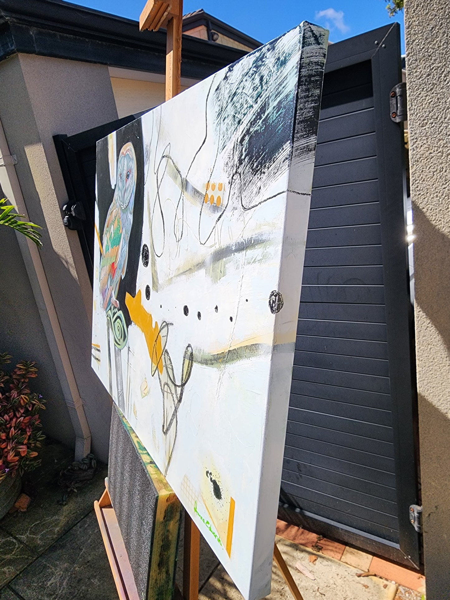 Large abstract painting side view displayed outdoors on a stand