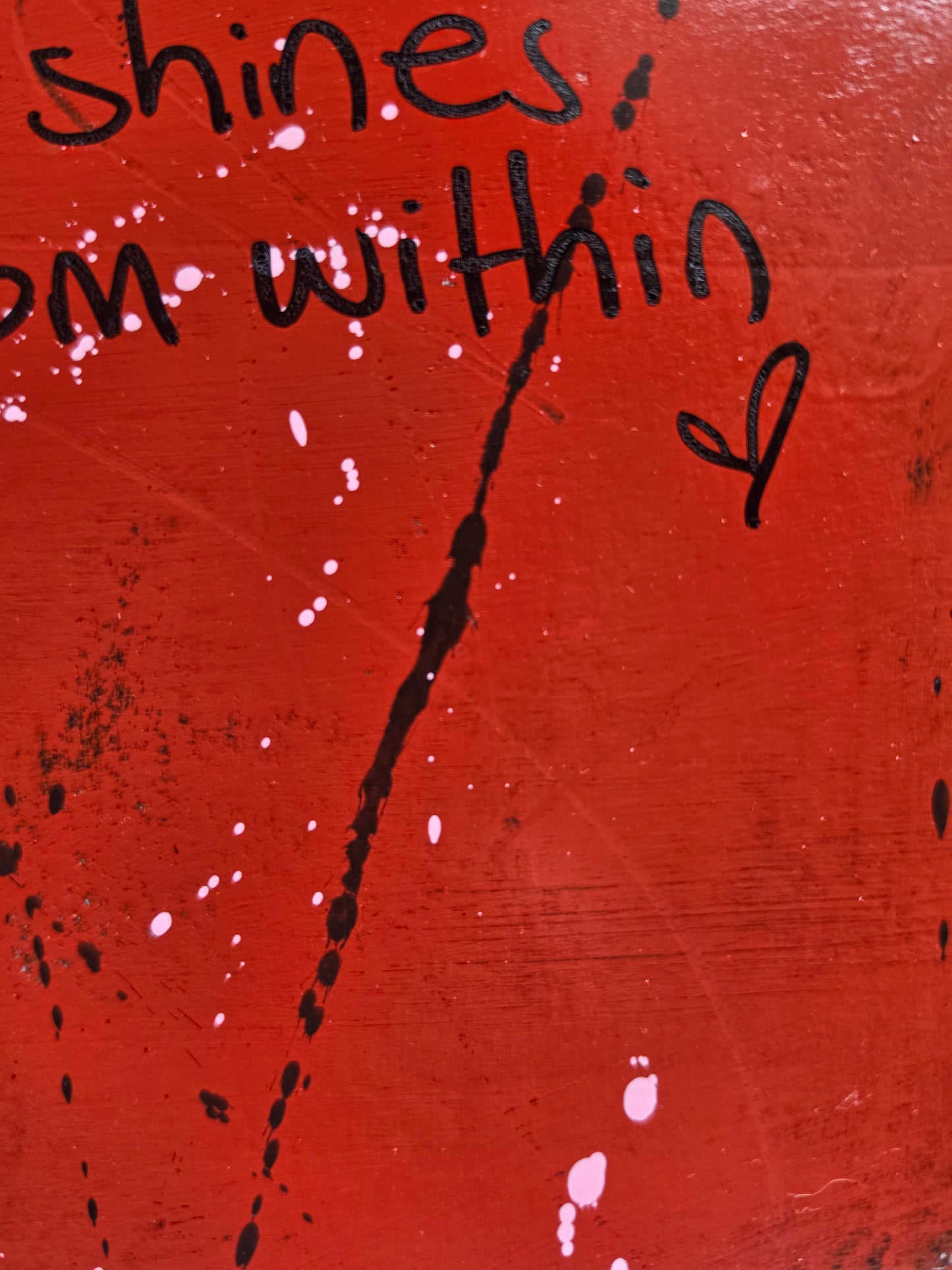 Red painting with black text and a heart symbol with black and pink spots