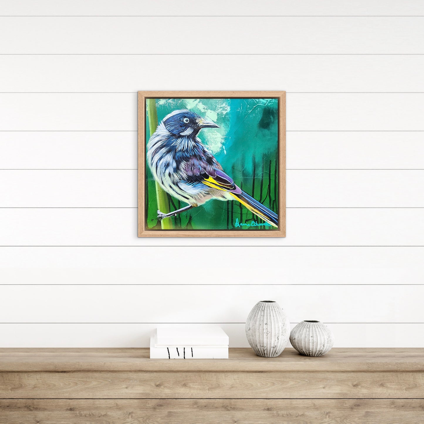 Framed artwork of a bird on a white wall with wooden shelf and decorative items.