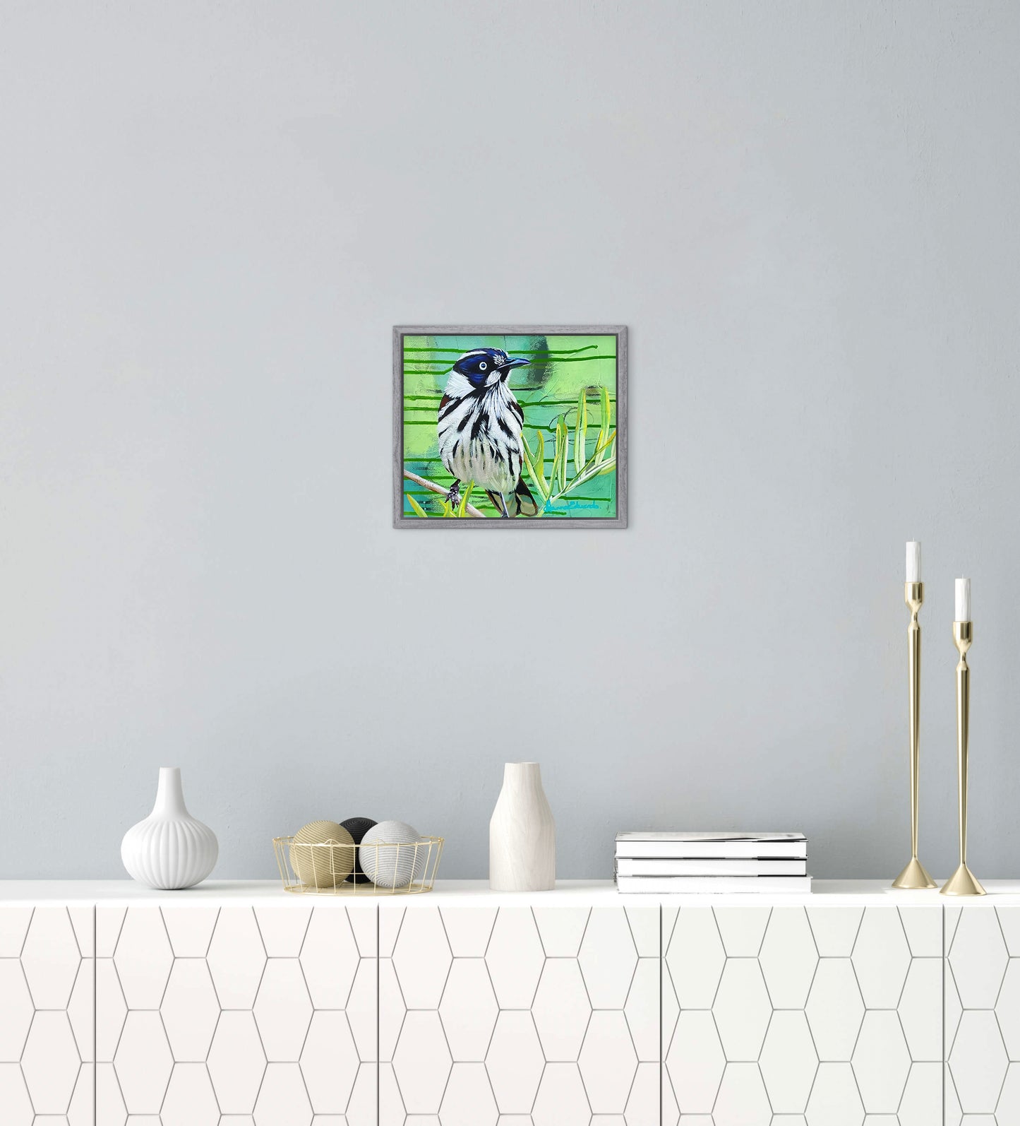 Framed artwork of a bird on a wall above a white console table with decorative items.