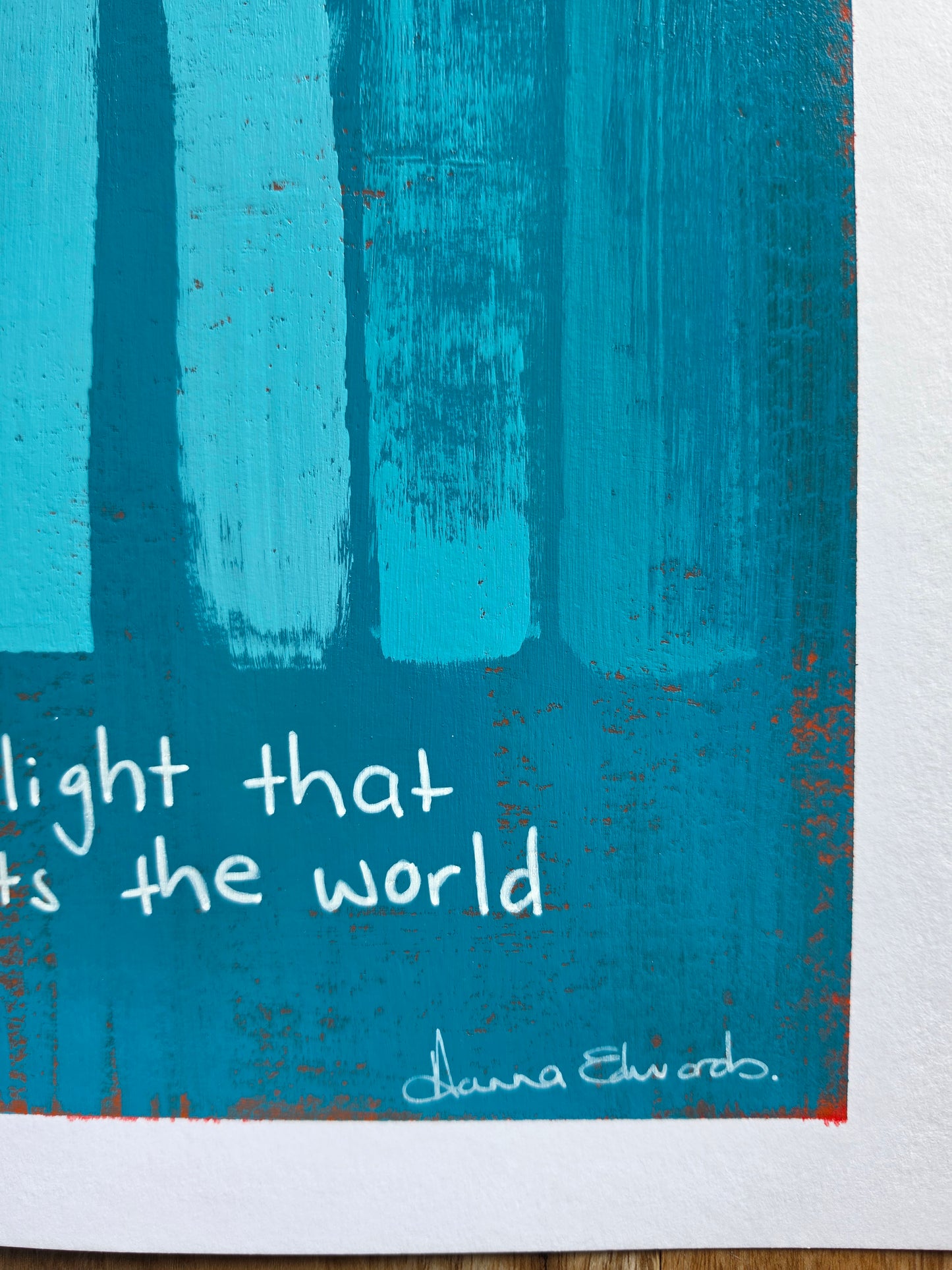 A close-up of a blue and turquoise art featuring vertical textured brushstrokes, white handwritten text and artist signature at the bottom right.