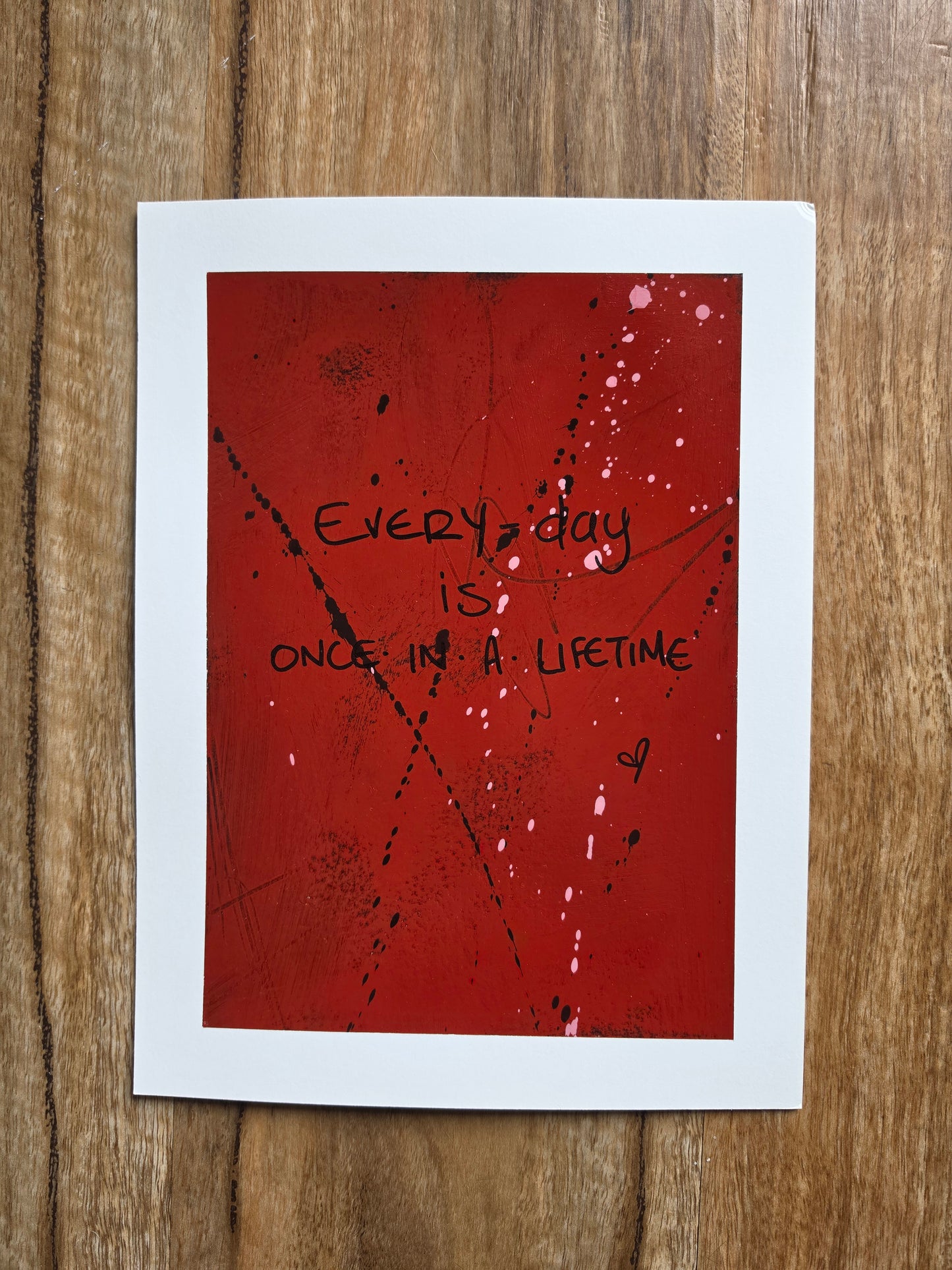 Red painting with black text Every day is  Once In A Lifetime with black spots and pink drips