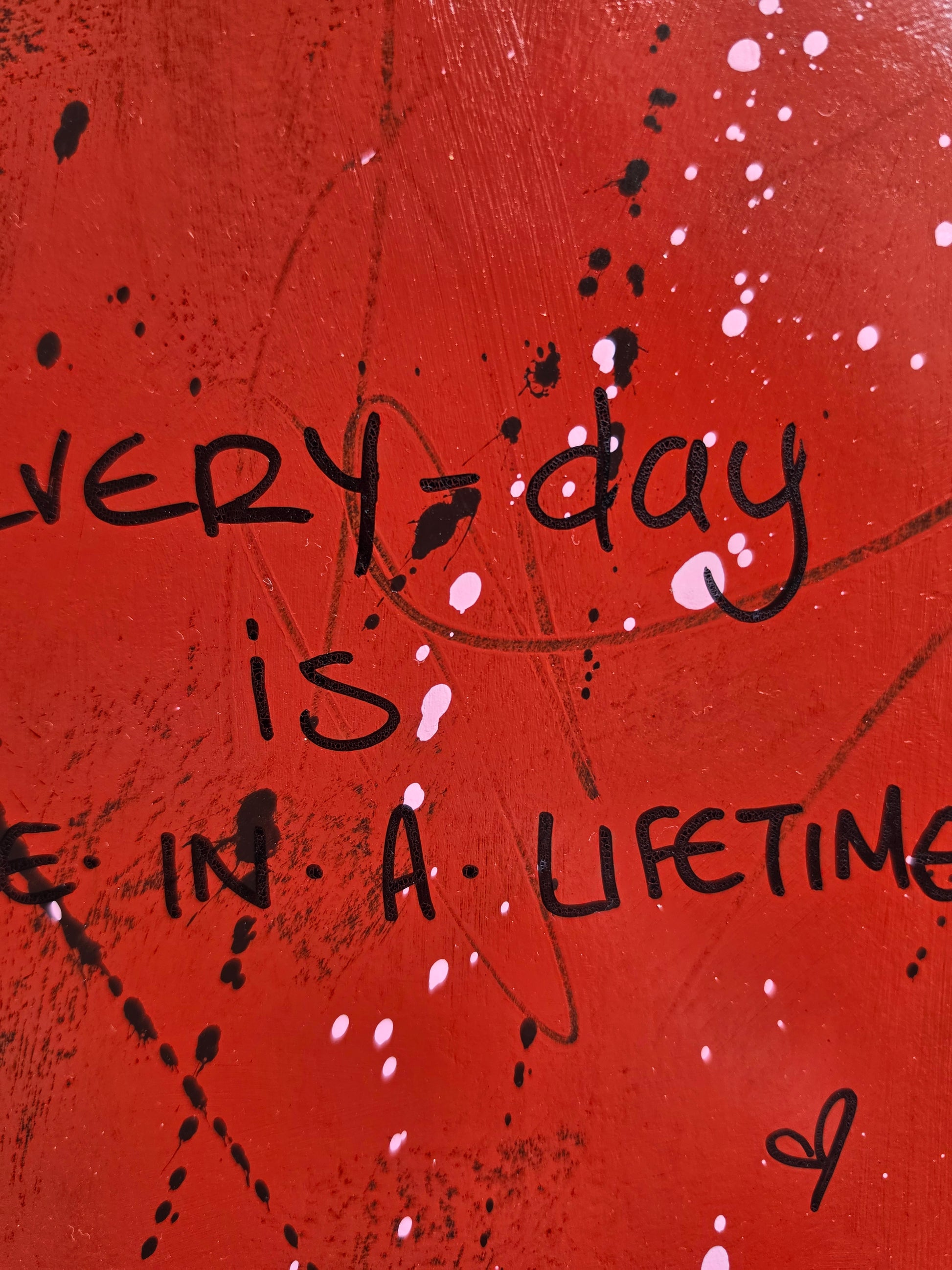Red painting close up with black text and splashes and texture
