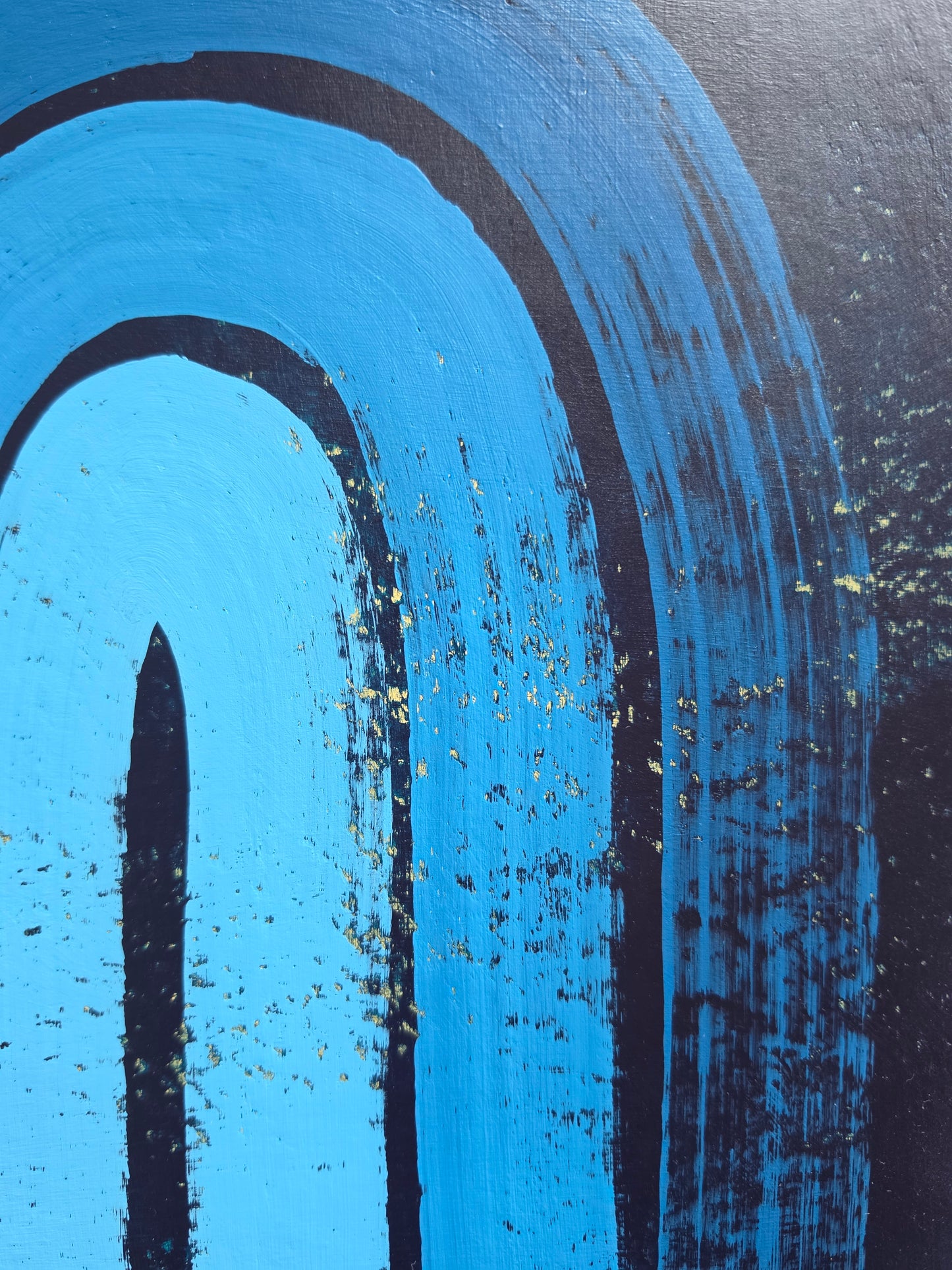 Blue painting with a blue monochromatic rainbow with pops of yellow from the underneath layers close up
