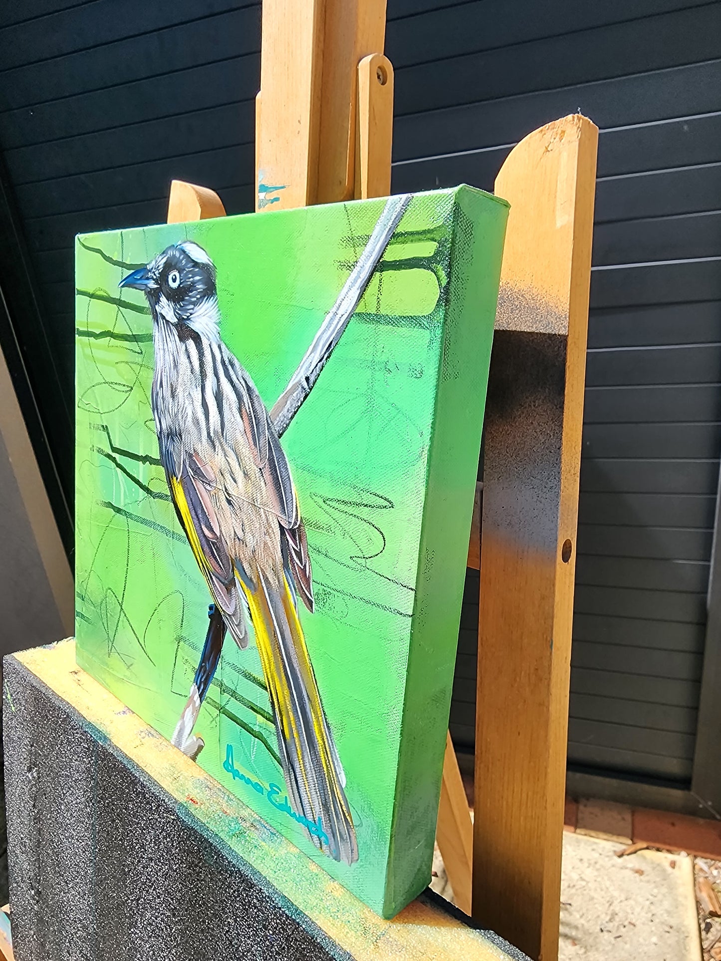 Bird painting on a green background side view displayed on a wooden easle 