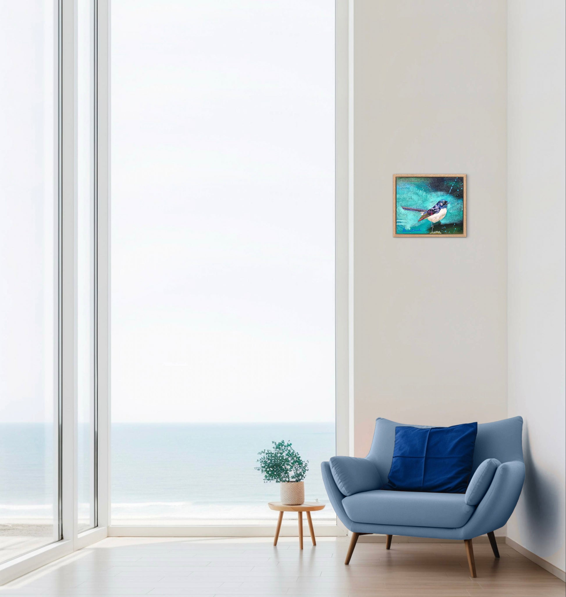 Modern living room with a blue armchair, small table, and framed artwork on a white wall.