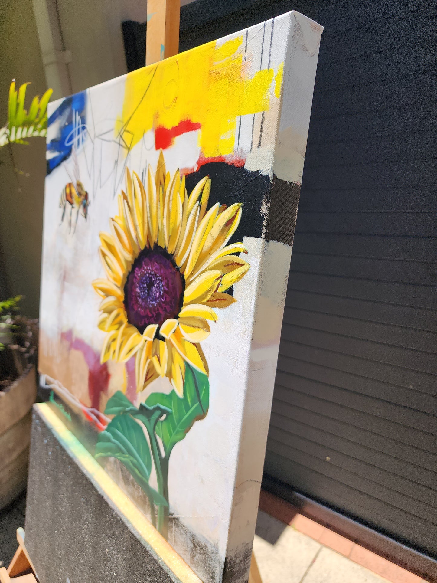 Canvas with a sunflower painting on a wooden easel side view