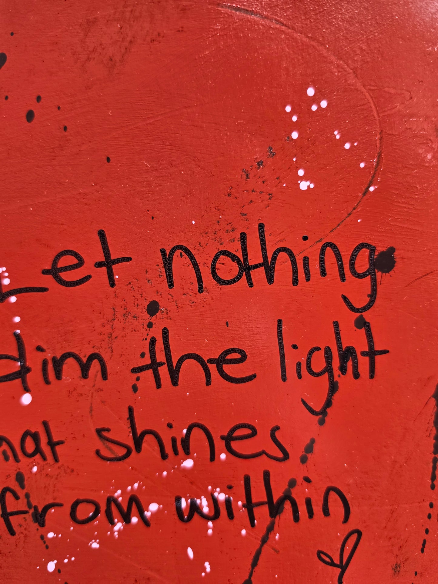 Red abstract painting with black text with some texture close up