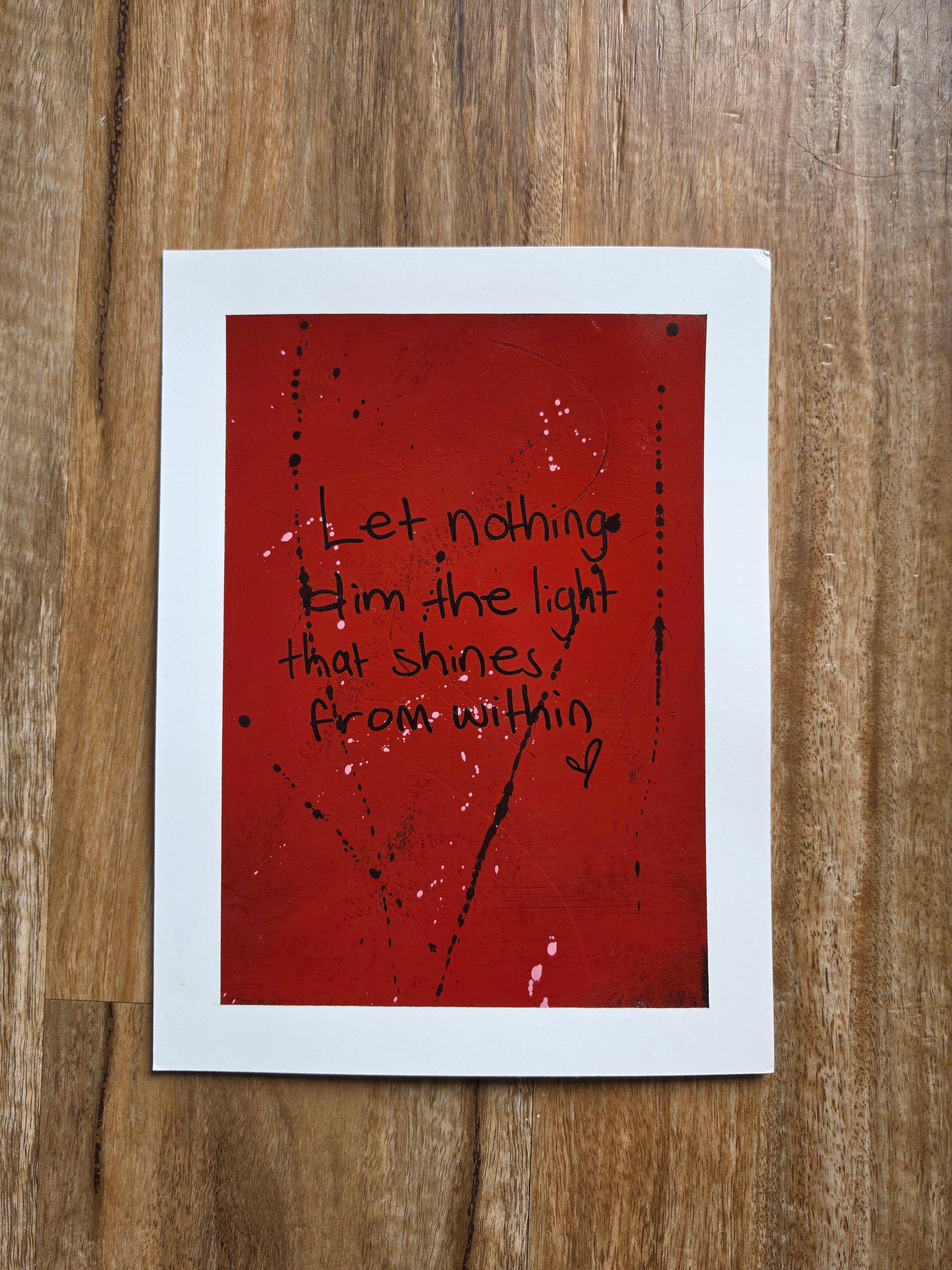 Red painting with the words let nothing dim the light that shines from within in black text on a wooden surface