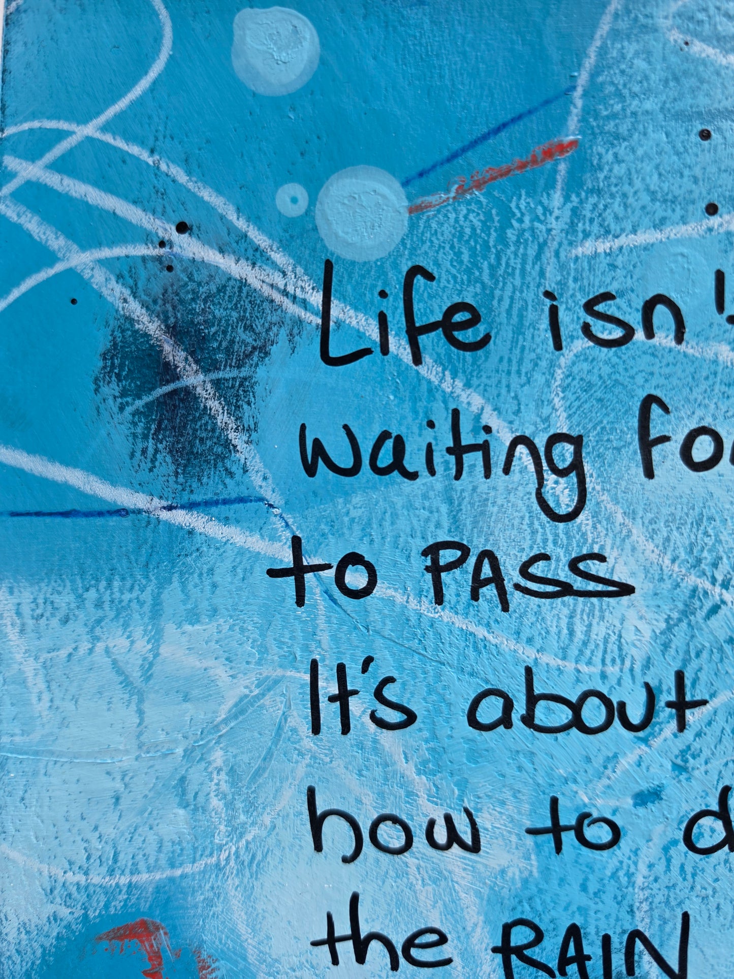 Close up of painting with black text on a blue background with abstract patterns