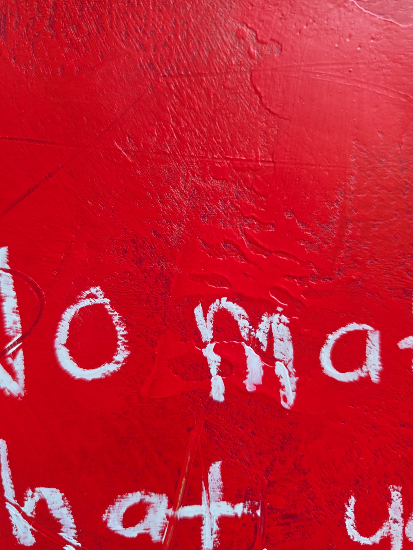 Close up of red painting with white text partially visible