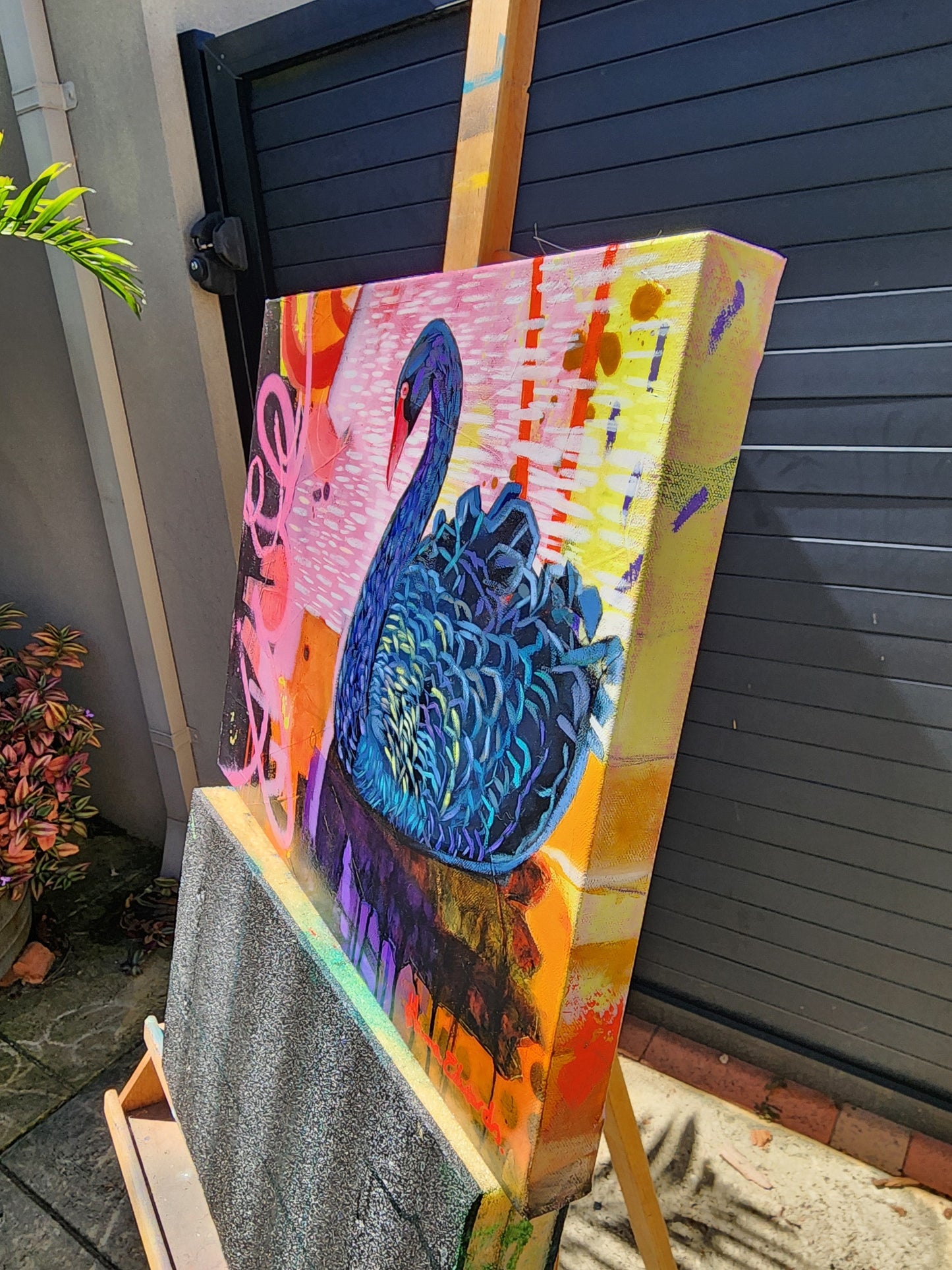 Colorful artwork with a black and  blue swan on a wooden surface