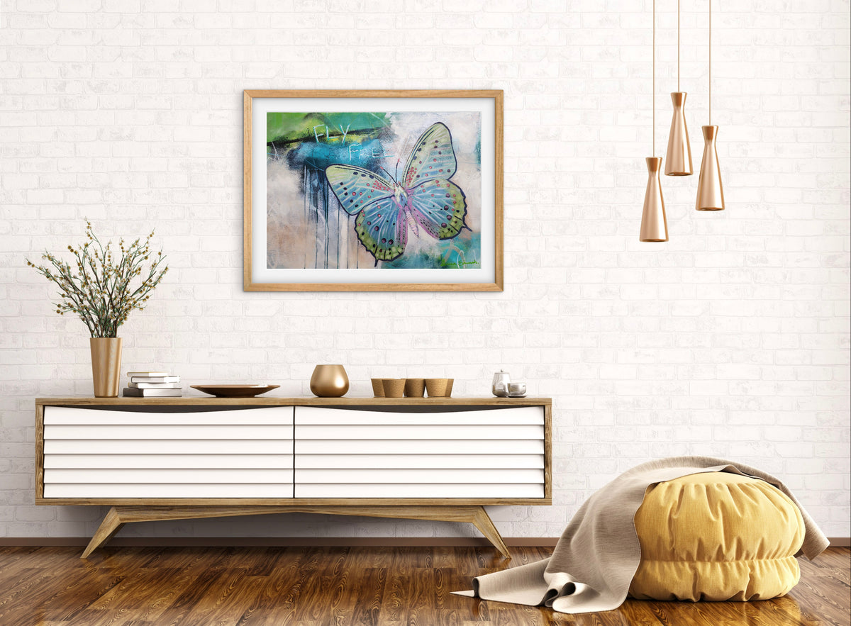 Fly Free butterfly artwork in blue, green and pink by Australian artist Hanna Edwards, on wall displayed in modern interior.