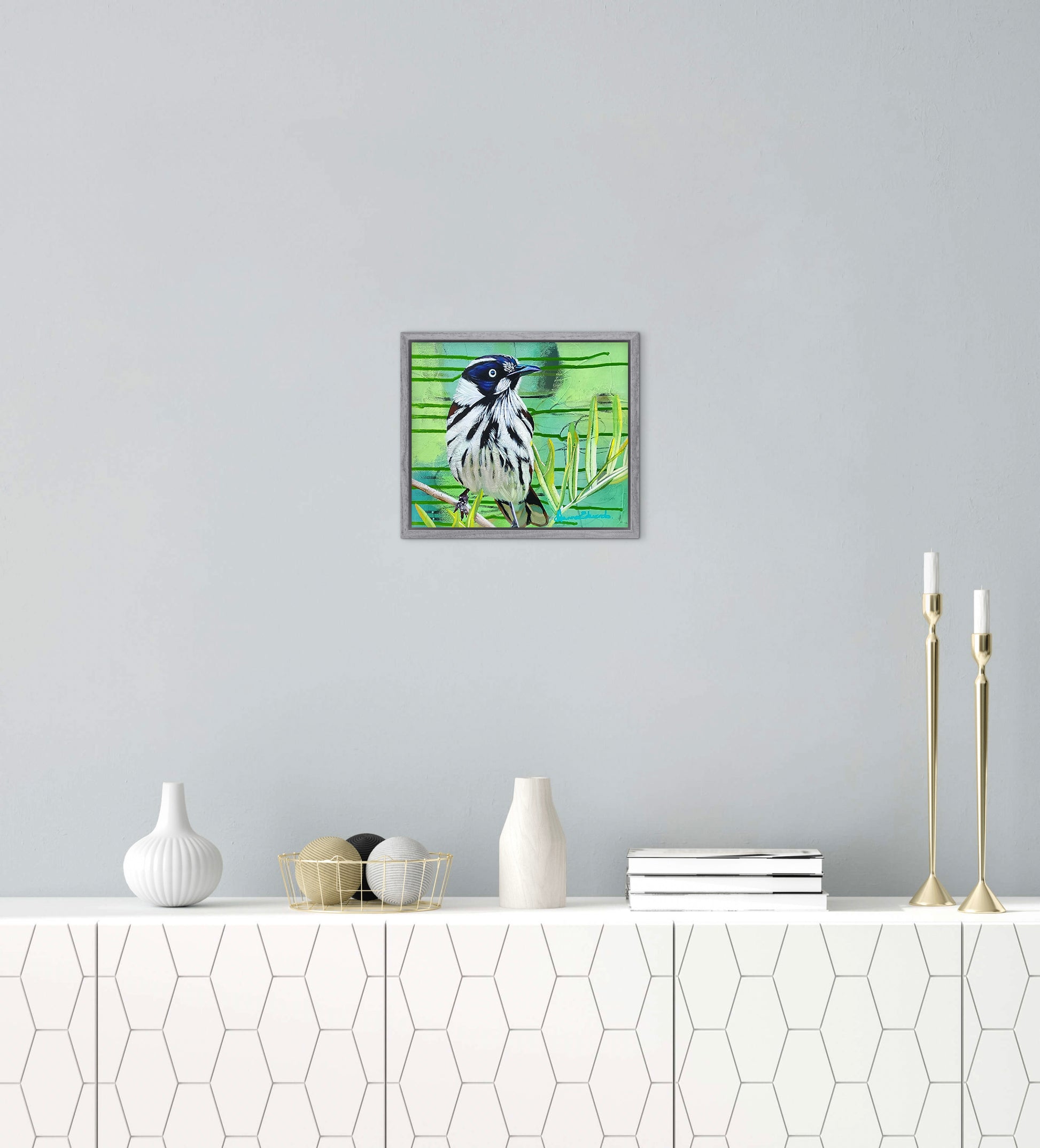 Framed artwork of a bird on a wall above a white console table with decorative items.