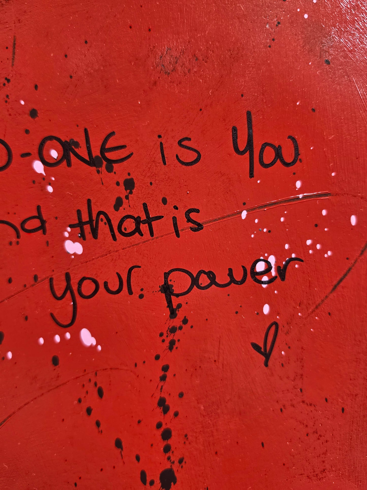 Red painting with black text, texture and splashes of pink paint 