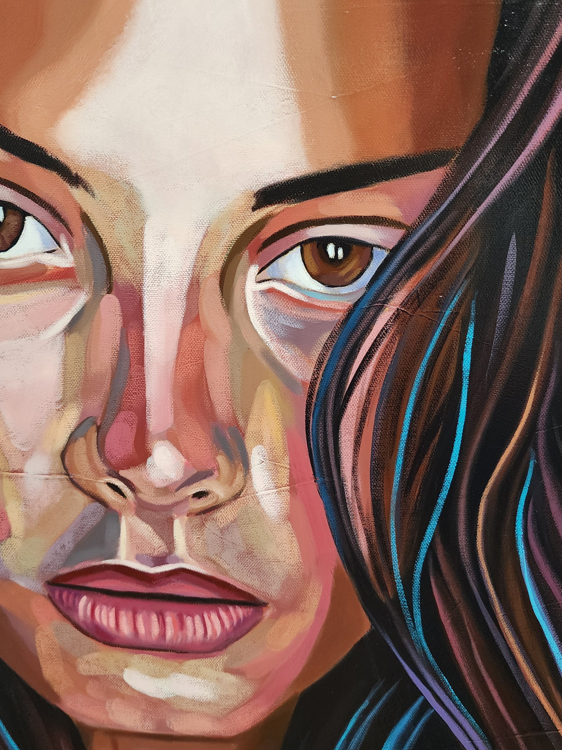 A close-up portrait painting of a woman's face with expressive brown eyes, peach and pink skin tones, dark brown hair, and vivid blue highlights.