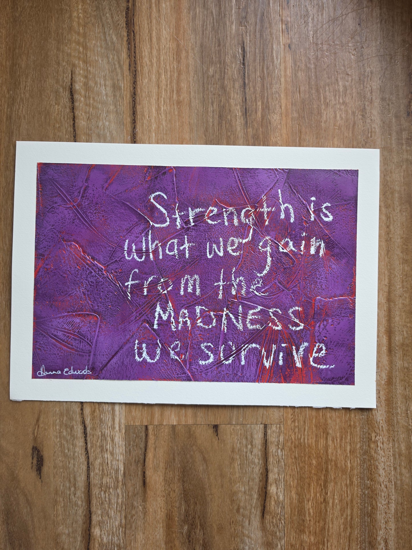 artwork features a textured purple background with red popping through the previous layers with white handwritten text reading, 'Strength is what we gain from the madness we survive.