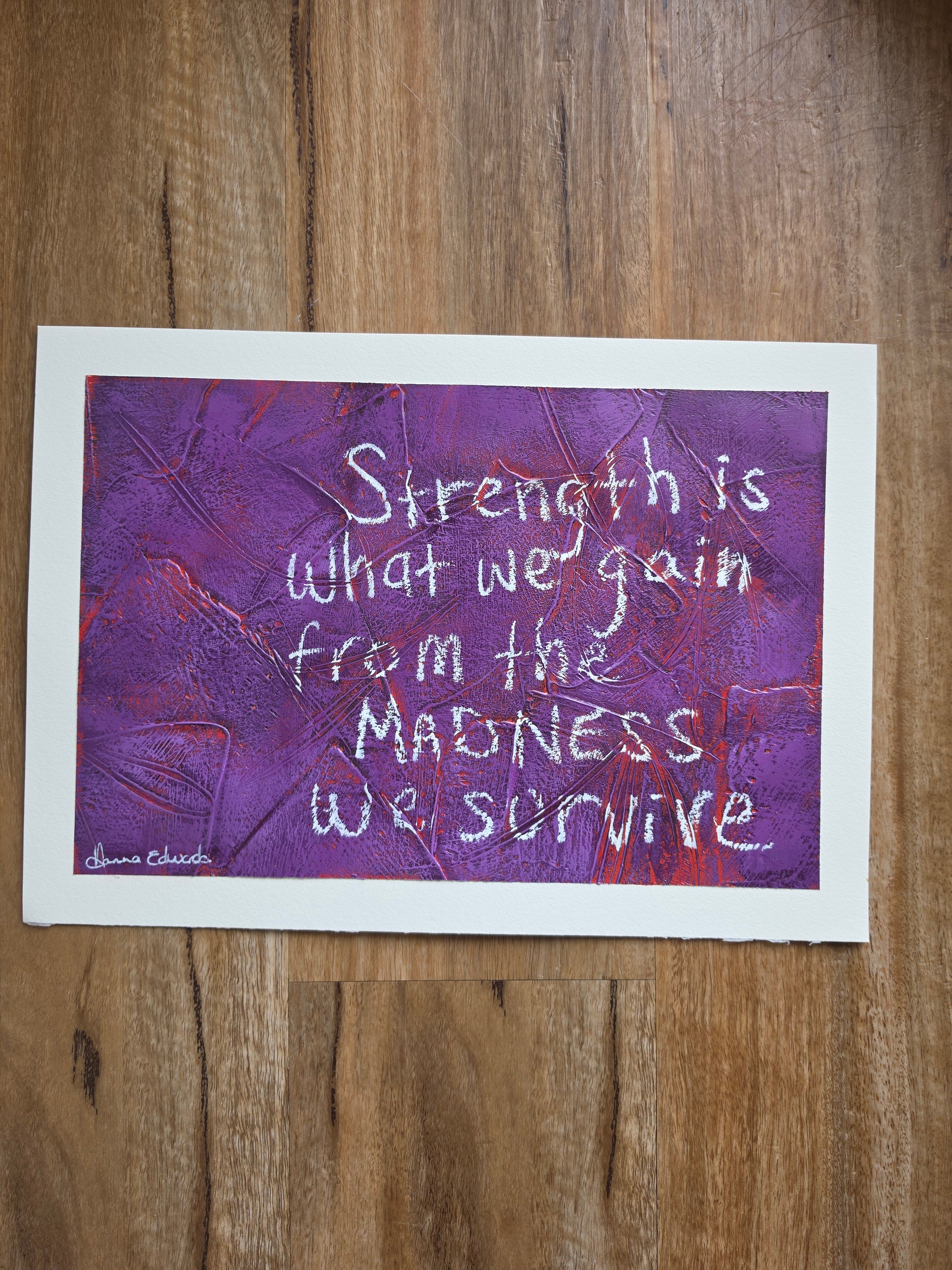 artwork features a textured purple background with red popping through the previous layers with white handwritten text reading, 'Strength is what we gain from the madness we survive.