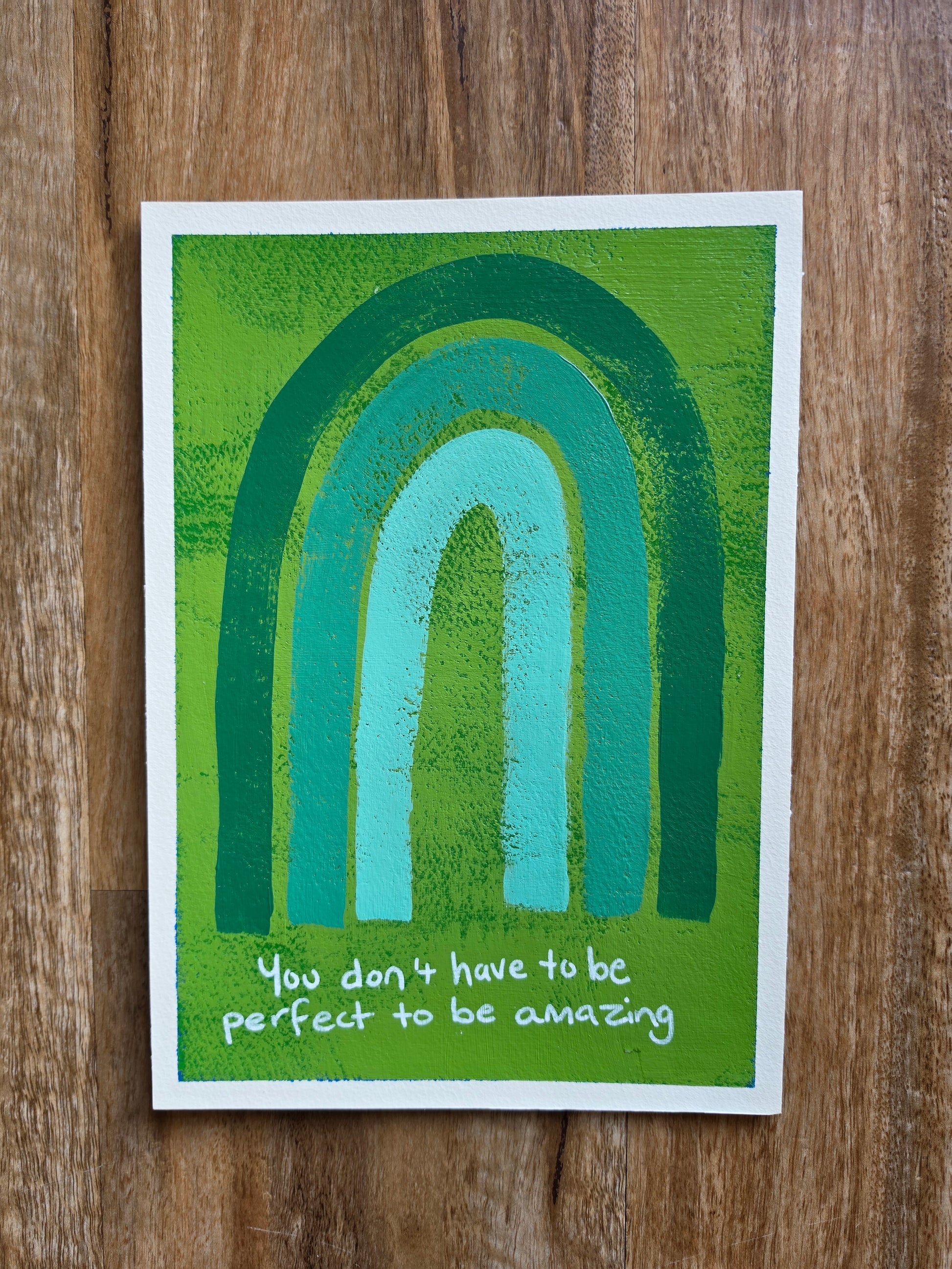 Green painting with monochromatic rainbow with the words You don't have to be perfect to be amazing in white handwriting