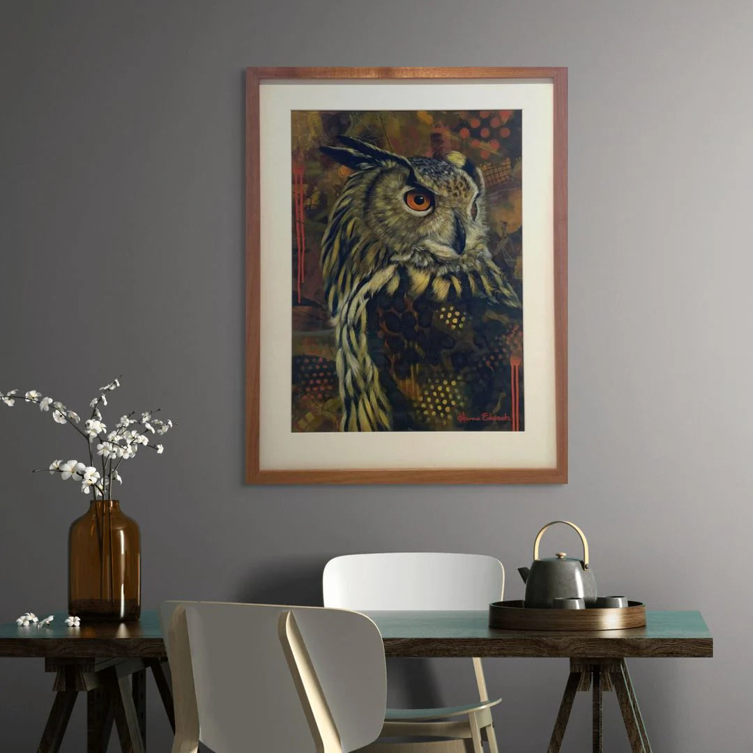 Framed artwork of an owl on a gray wall above a dining table with chairs.